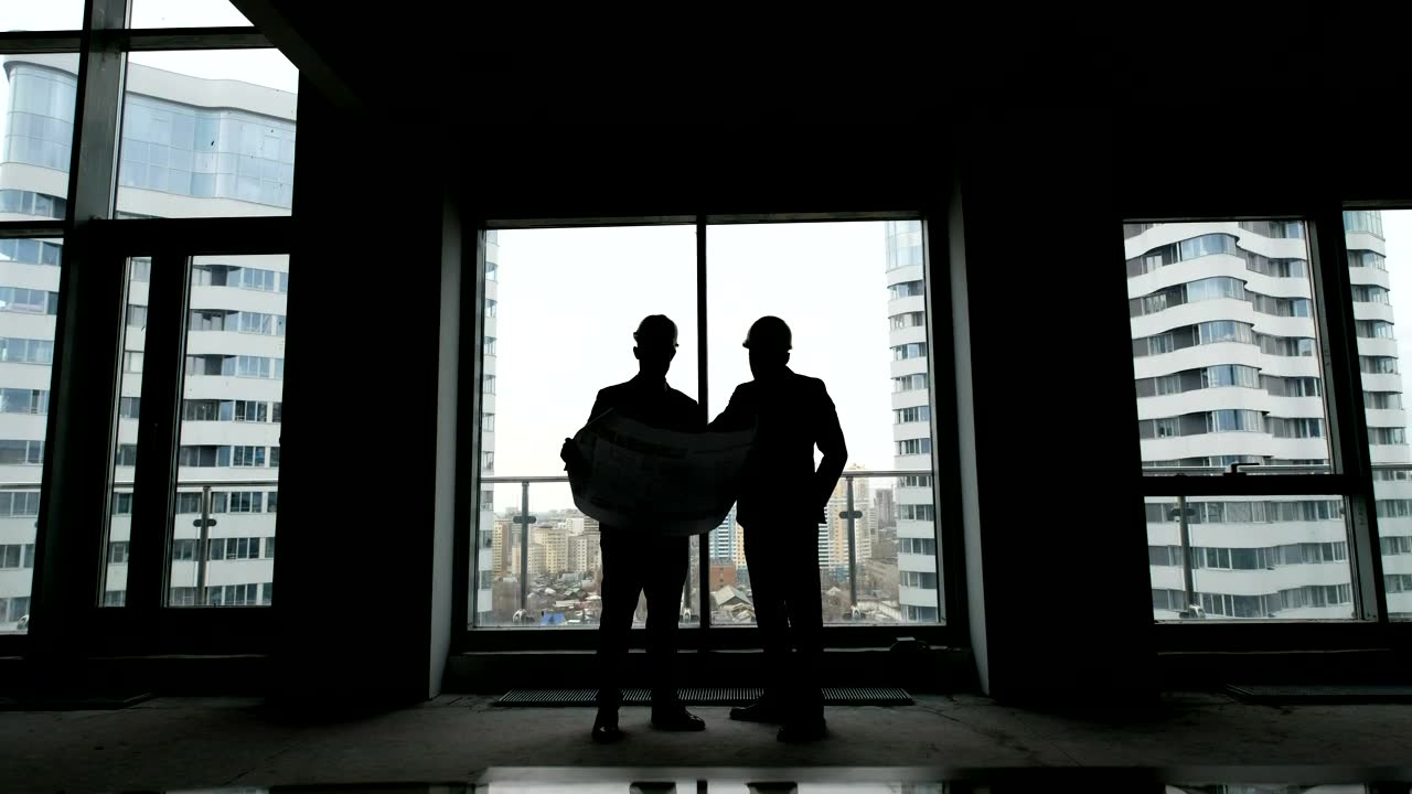 Two estimators reviewing a drawing set in a building under construction